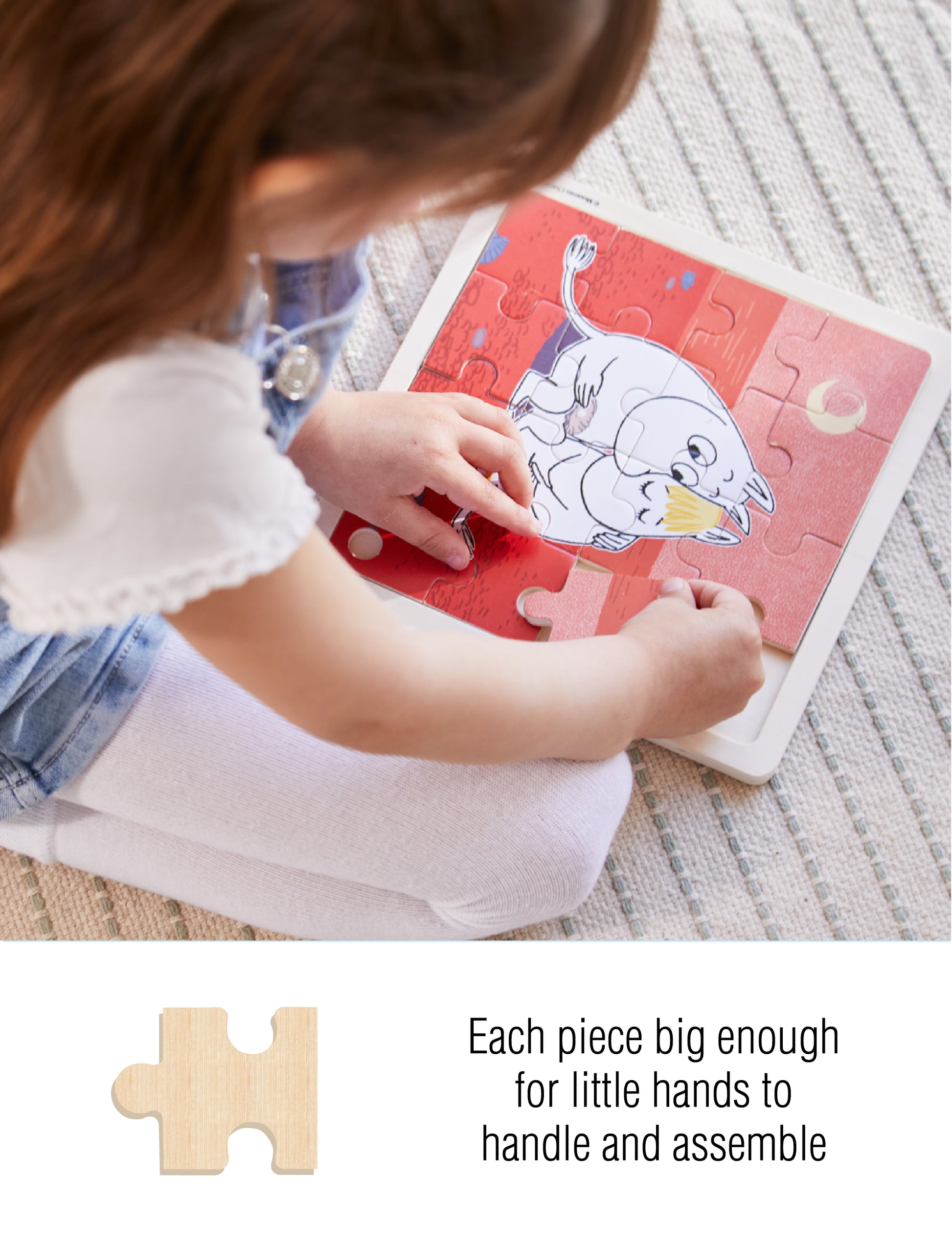 Child assembling a Moomin wooden puzzle with large pieces, designed for small hands. Text on image: 'Each piece big enough for little hands to handle and assemble'.