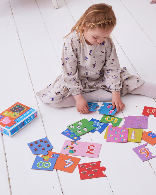 Girl sitting on floor playing with peppa pig matching game